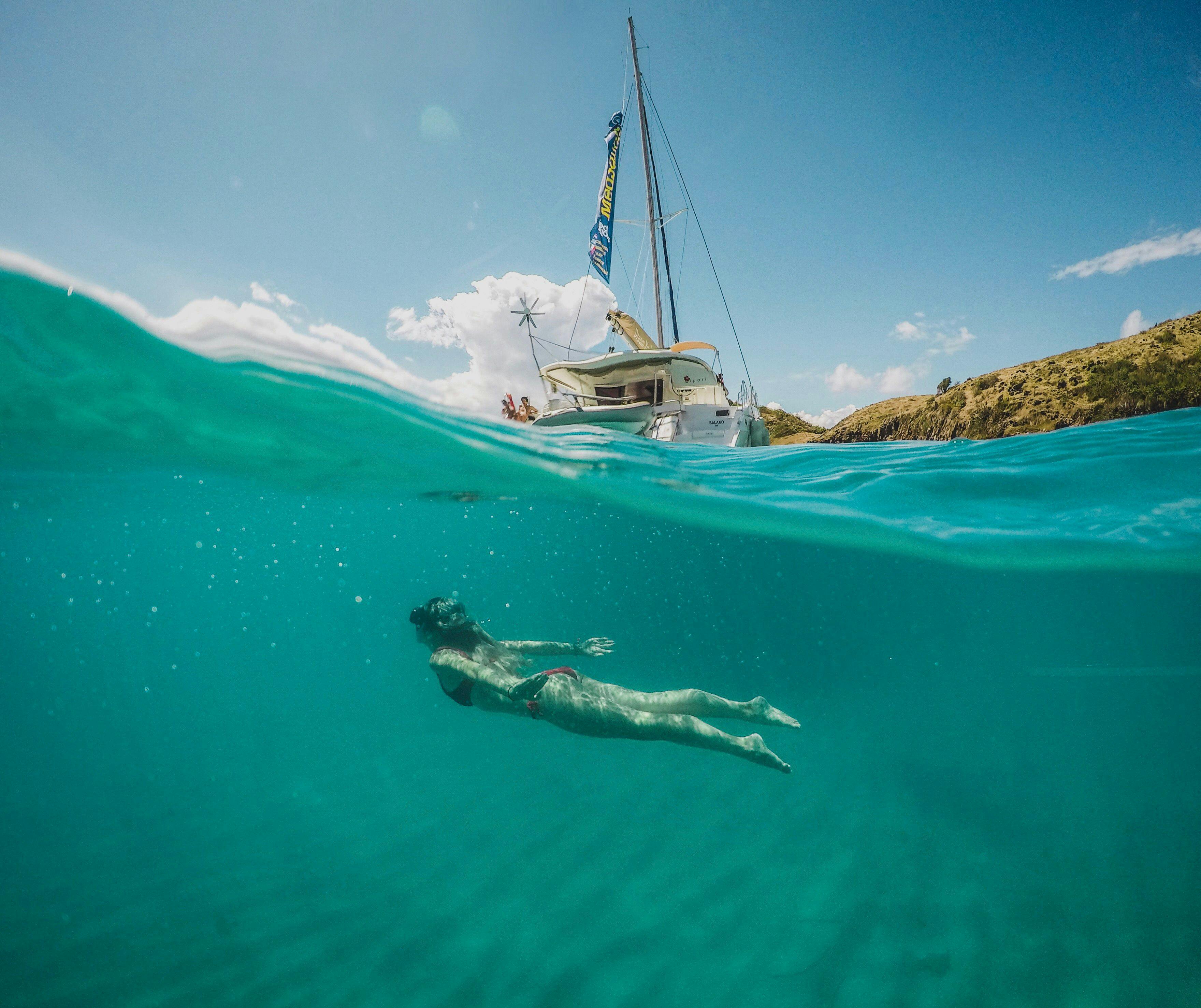 Woman snorkelling underwater next to a MedSailors catamaran