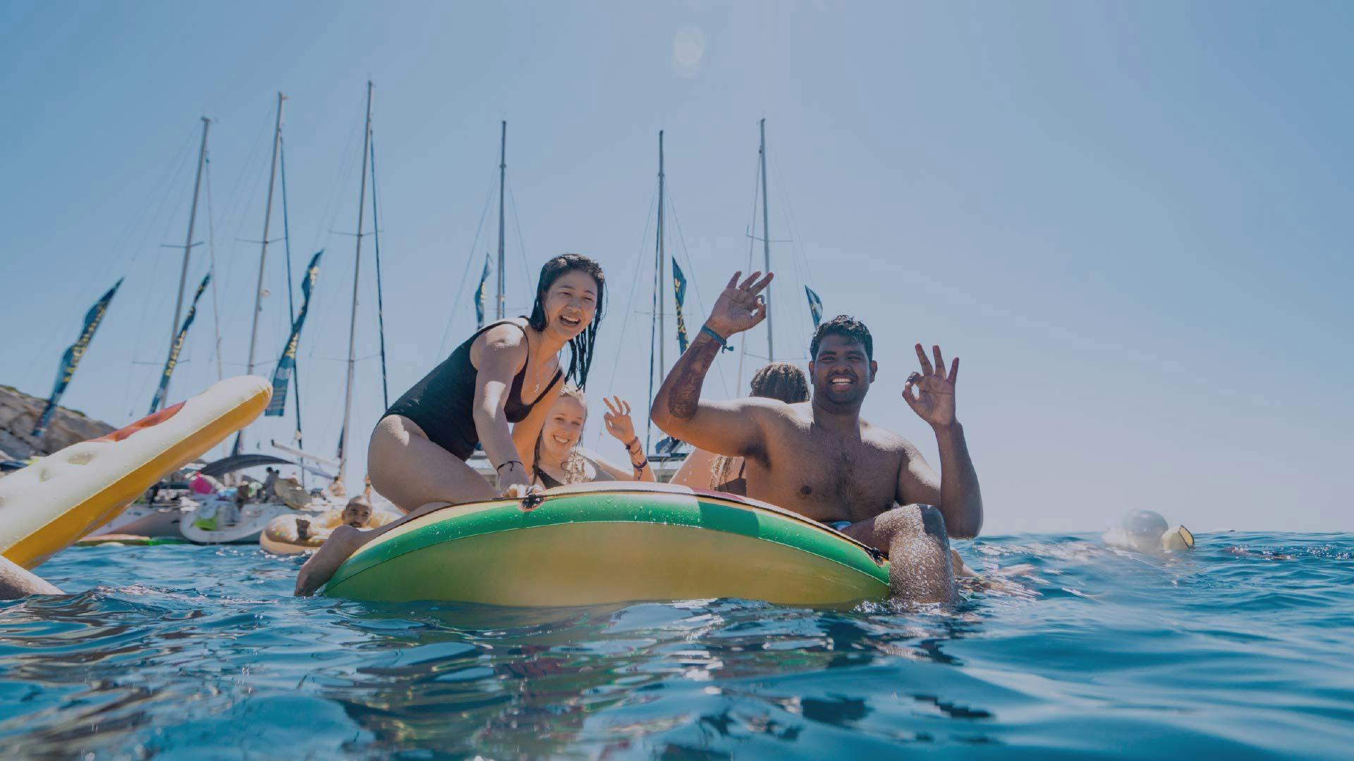 Friends having fun on floaties in front of MedSailors yachts