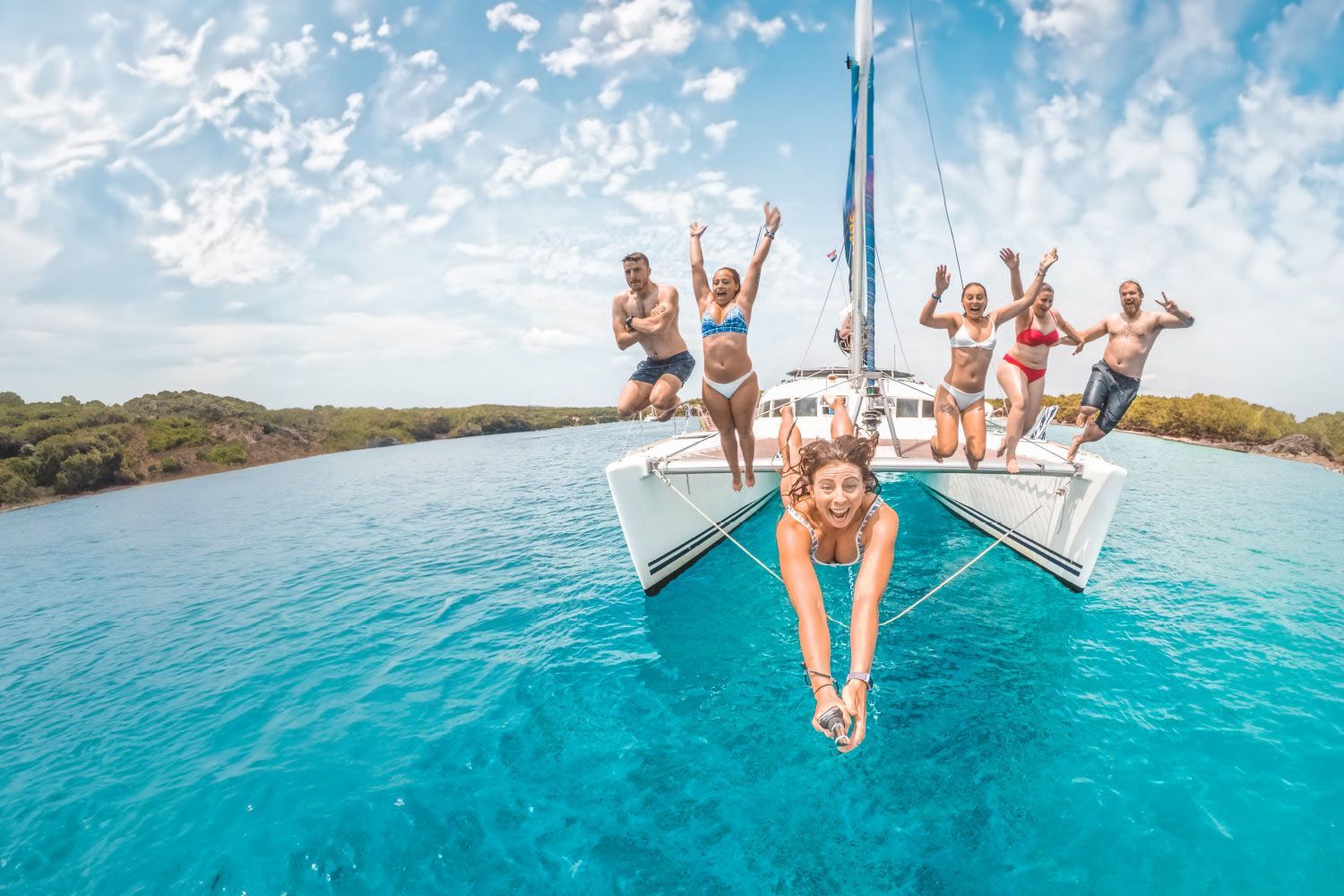 Group of people jump off a catamaran into the water in Croatia